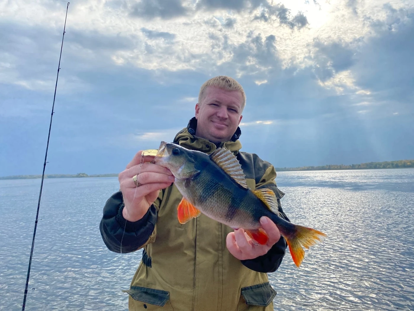 Рыболов с окунем на воде